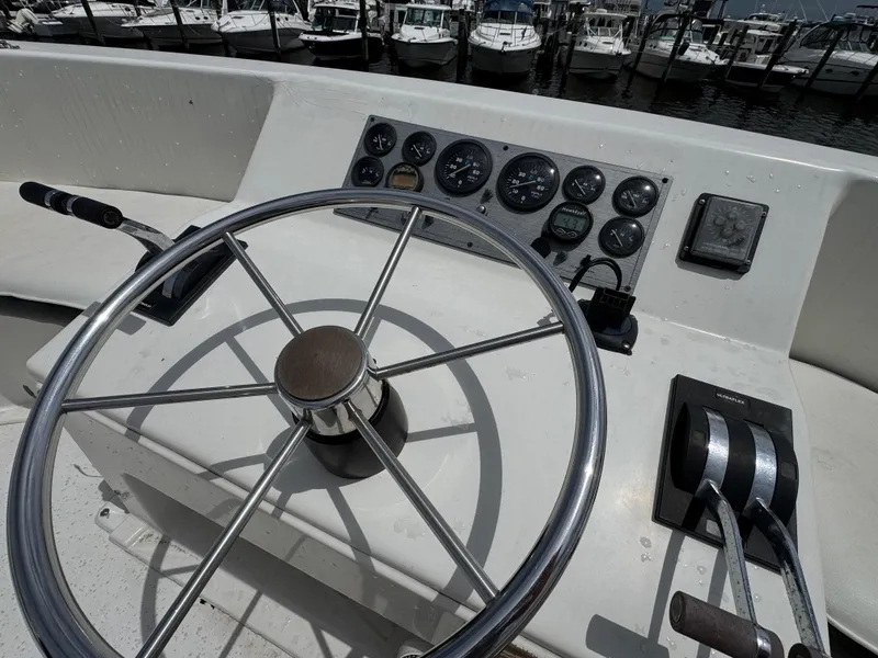 Slide: The Image of Steering wheel and controls of a 1993 Gibson 37 Sport Series boat at a marina. - 9