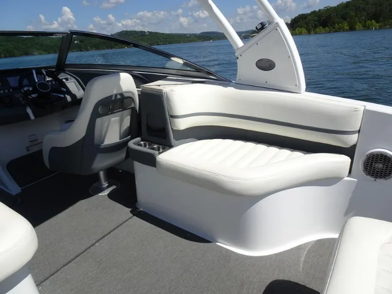 Slide: The Image of 2016 Cobalt R7 boat interior with white seating and steering wheel, on a lake. - 8