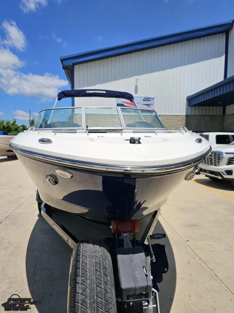 Slide: The Image of 2020 Chaparral 21 SSi boat on trailer, parked outdoors under clear blue sky. - 15