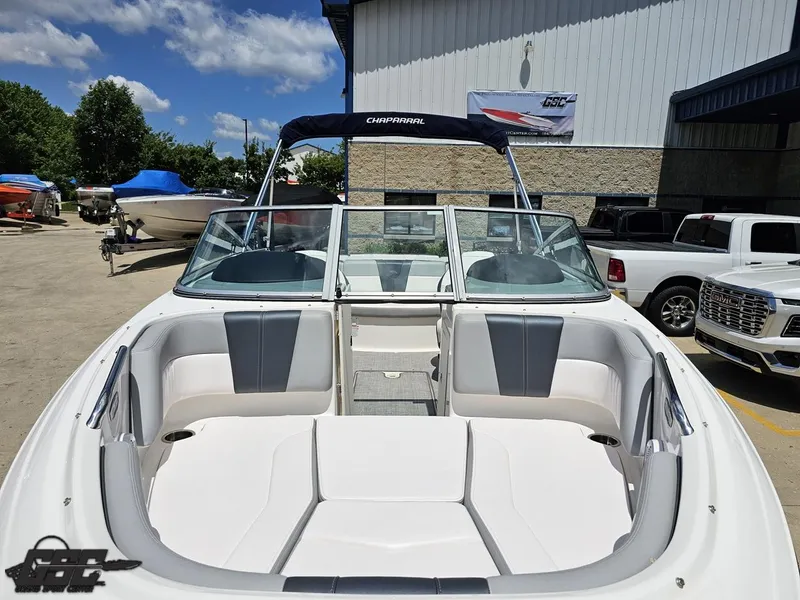 Slide: The Image of 2020 Chaparral 21 SSi boat with open bow seating, parked outdoors under a clear sky. - 17
