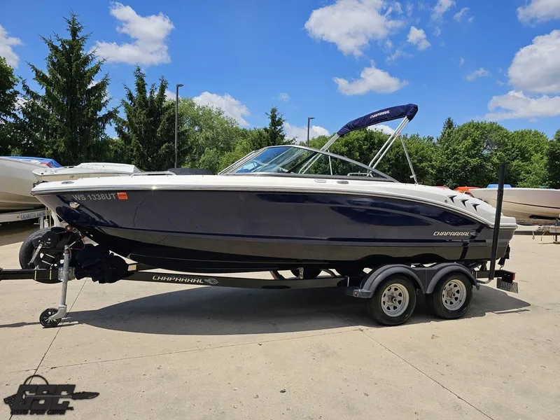 Slide: The Image of 2020 Chaparral 21 SSi boat on trailer, parked outdoors under a clear blue sky. - 22