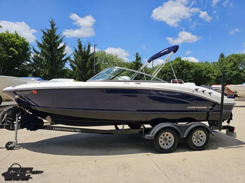 Slide: The Image of 2020 Chaparral 21 SSi boat on trailer, parked outdoors under a clear blue sky. - 23