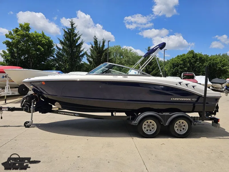 Slide: The Image of 2020 Chaparral 21 SSi boat on trailer, parked outdoors under a clear blue sky. - 24