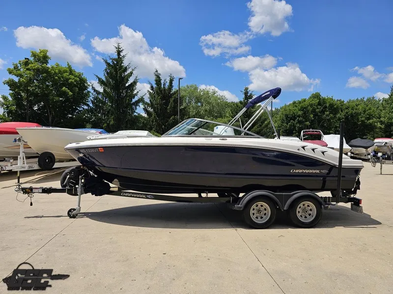 Slide: The Image of 2020 Chaparral 21 SSi boat on trailer, parked outdoors under a clear blue sky. - 25