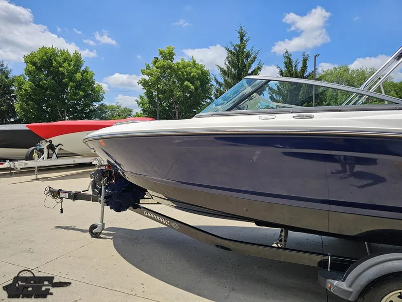 Slide: The Image of 2020 Chaparral 21 SSi boat on trailer, parked outdoors under a clear blue sky. - 27