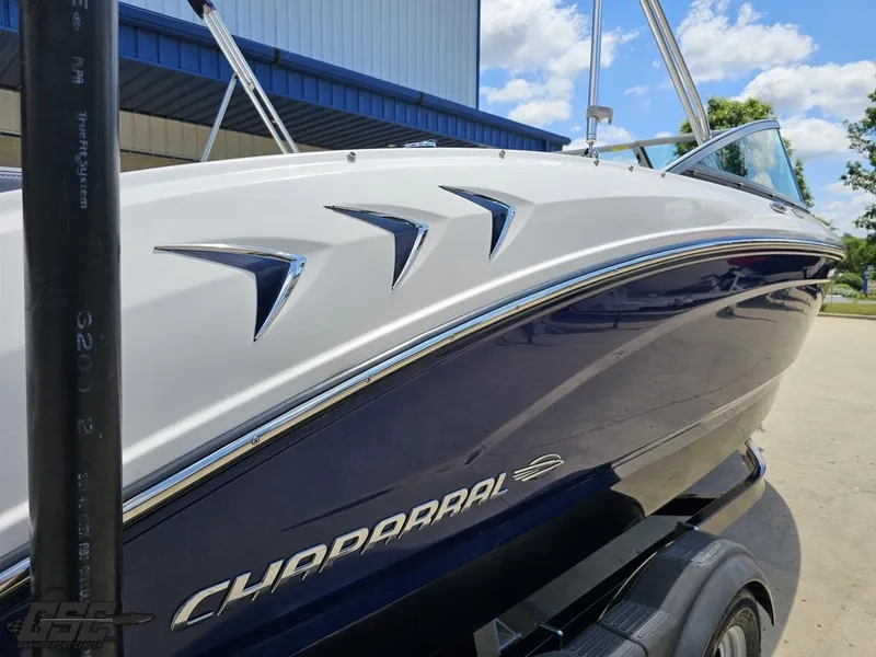 Slide: The Image of 2020 Chaparral 21 SSi boat, sleek design, parked outdoors under blue sky. - 40