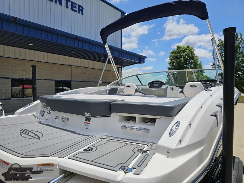 Slide: The Image of 2020 Chaparral 21 SSi boat with sleek design, docked near a building under a clear sky. - 43