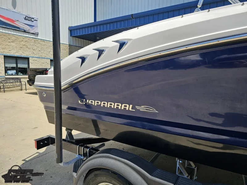 Slide: The Image of 2020 Chaparral 21 SSi boat on trailer, blue and white exterior, parked outside. - 7
