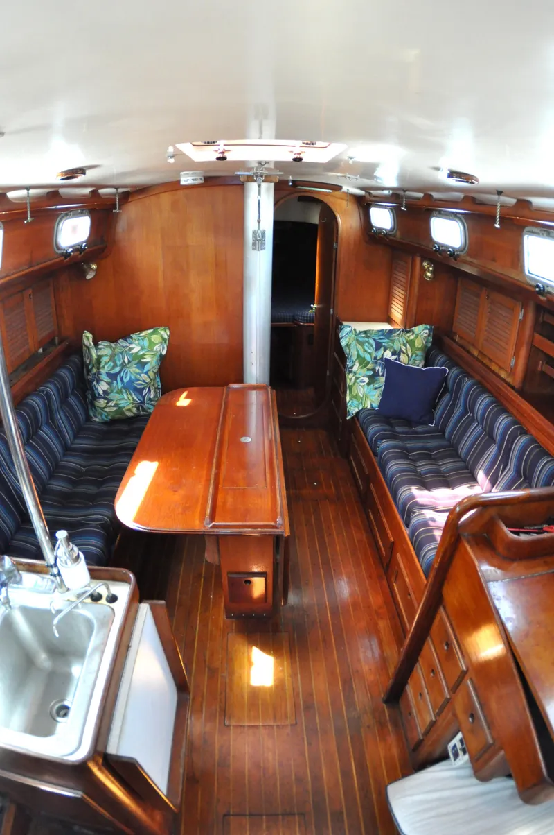 Slide: The Image of 1984 Bristol 38.8 yacht interior with wooden finish, striped seating, and compact kitchen area. - 11