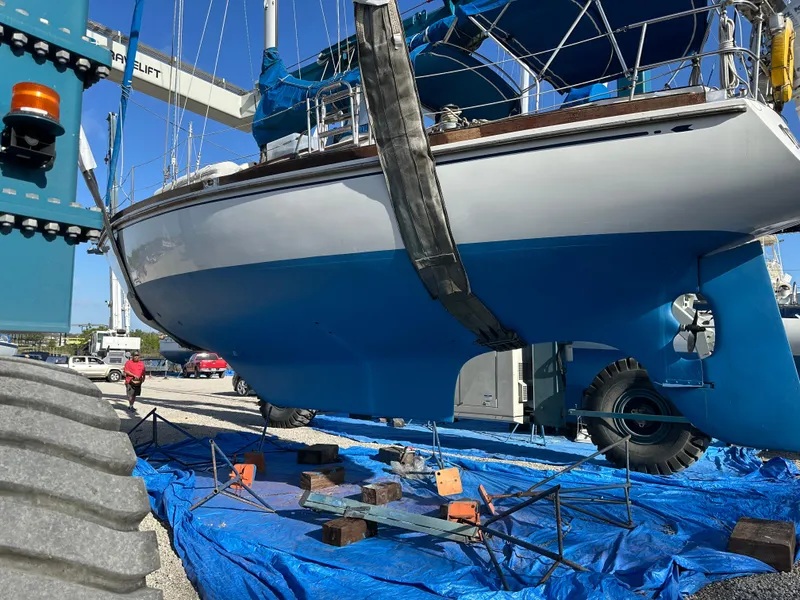 Slide: The Image of 1984 Bristol 38.8 sailboat on blue tarp, supported by a travel lift in a boatyard. - 5