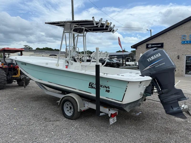 Slide: The Image of 2011 Carolina Skiff 218 DLV boat with Yamaha engine on trailer, parked outside a building. - 3