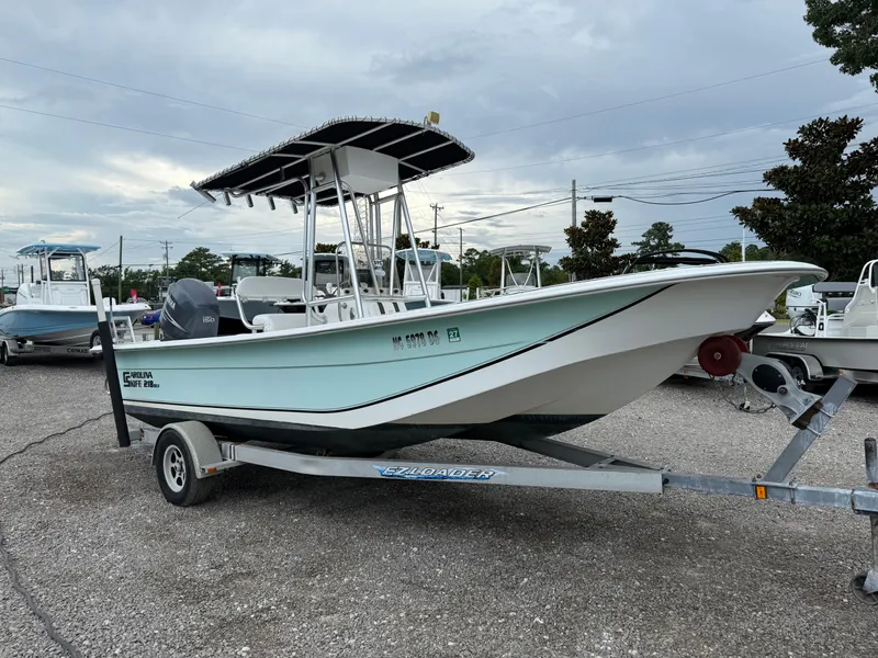 Slide: The Image of 2011 Carolina Skiff 218 DLV boat on trailer, parked outdoors under cloudy sky. - 8