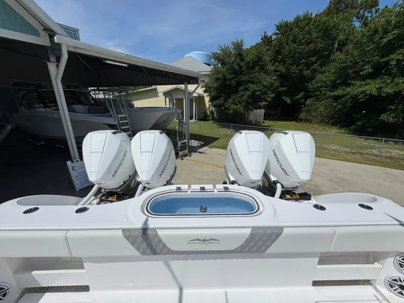 Slide: The Image of 2026 Invincible 38 Catamaran with four Mercury outboard engines, docked near a boatyard. - 37