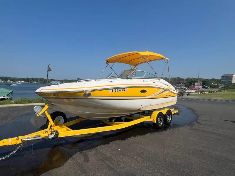 Slide: The Image of 2013 Hurricane SunDeck 2200 DC IO boat on yellow trailer by a lake. - 13