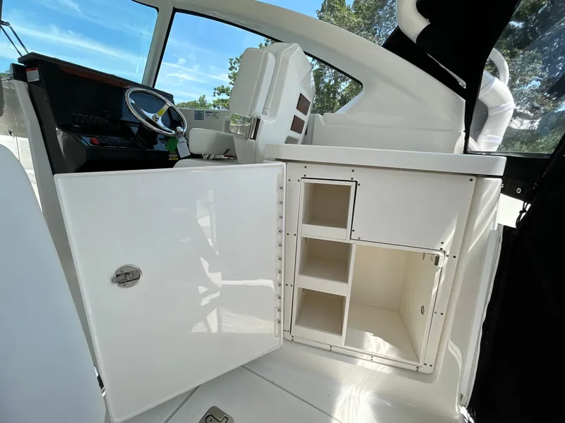 Slide: The Image of 2026 Pursuit DC 306 boat interior with open storage compartments and steering wheel. - 17