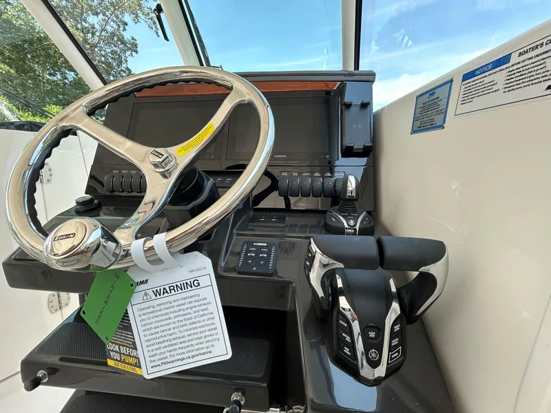 Slide: The Image of Steering console of 2026 Pursuit DC 306 boat with controls and warning tags. - 23