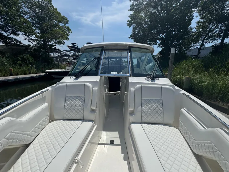 Slide: The Image of 2026 Pursuit DC 306 boat with white quilted seating, docked near lush greenery. - 37