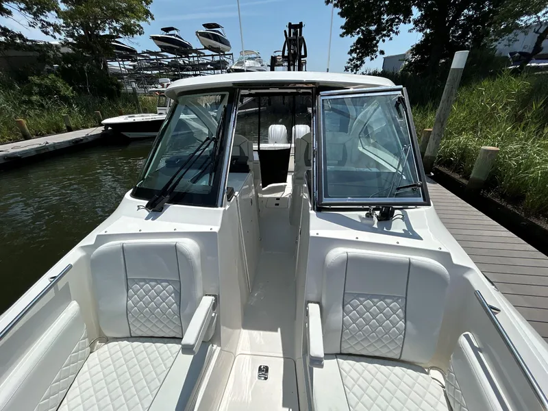 Slide: The Image of 2026 Pursuit DC 306 boat with white seating, docked near lush greenery. - 38