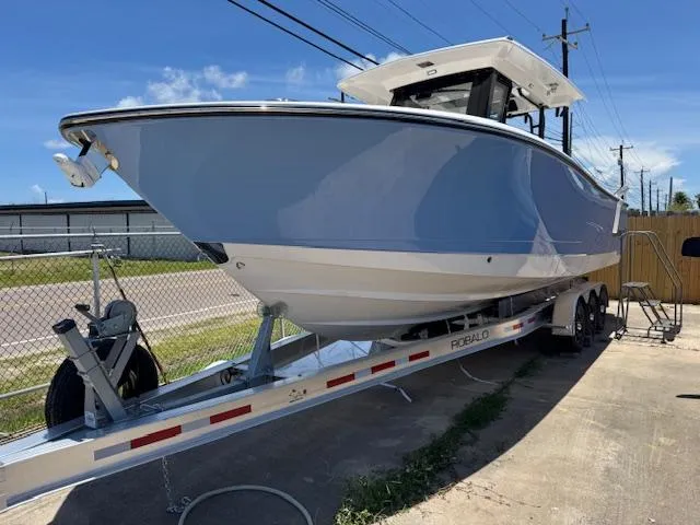 The Image of 2025 Robalo R300 Center Console boat on trailer, parked outdoors. - 1