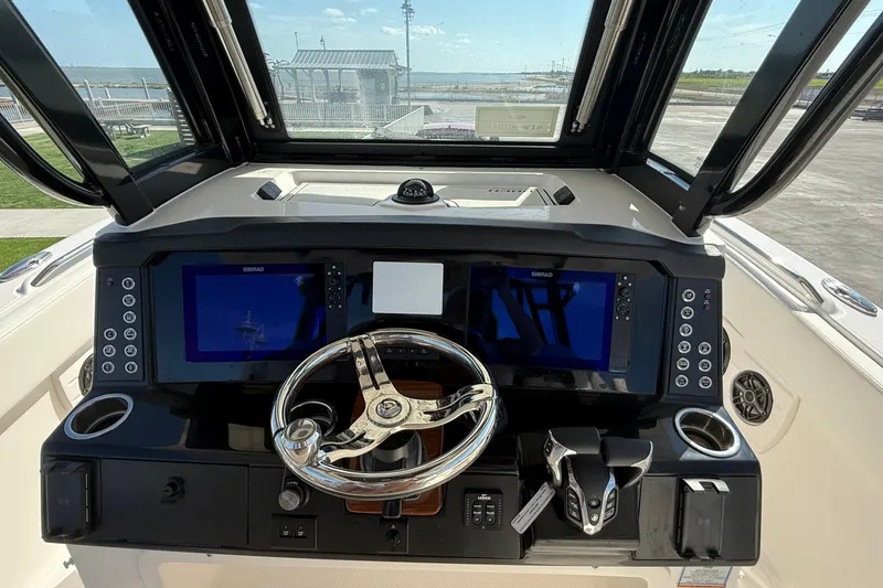 Slide: The Image of 2025 Robalo R300 Center Console boat dashboard with dual screens and steering wheel. - 10