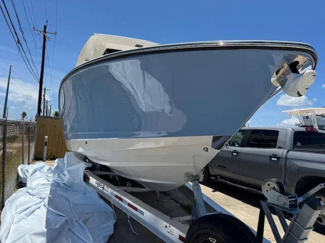 Slide: The Image of 2025 Robalo R300 Center Console boat on trailer, parked outdoors under clear blue sky. - 2