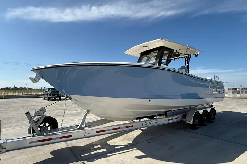 Slide: The Image of 2025 Robalo R300 Center Console boat on trailer under clear blue sky. - 8