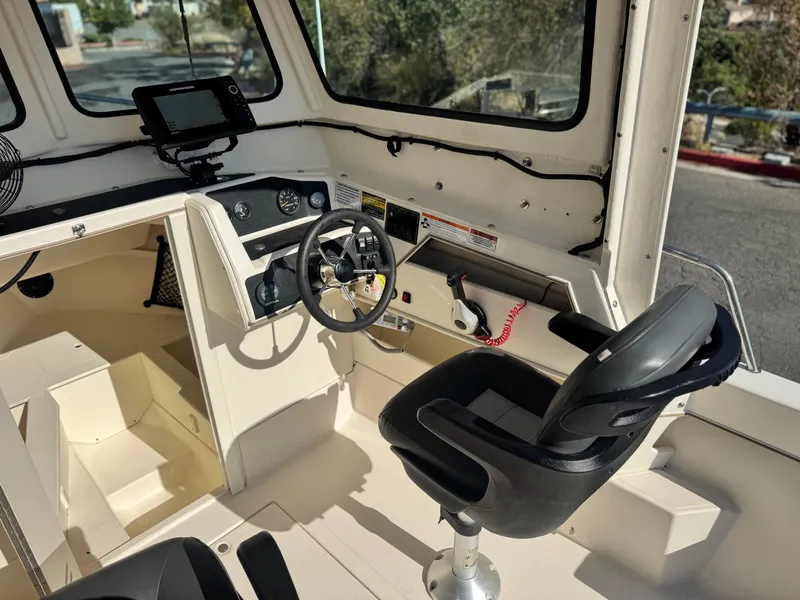 Slide: The Image of Interior of 2020 Arima Sea Chaser 19 Yellowtail Edition boat, featuring steering wheel and controls. - 19