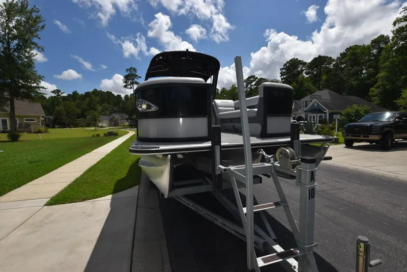 Slide: The Image of 2023 Bentley Pontoons 250 Elite Swingback Dual Captain on trailer, residential neighborhood background. - 3