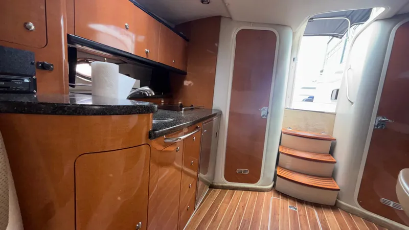 Slide: The Image of 2007 Chaparral Signature 330 interior with wooden cabinetry, compact kitchen, and stairs leading to deck. - 30