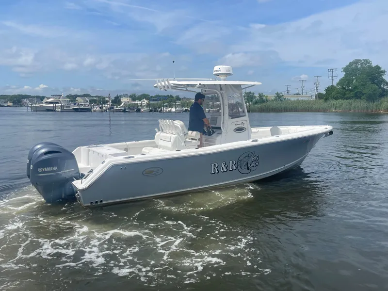 Slide: The Image of 2016 Sea Hunt Gamefish 27 boat on water, side view, with bridge and building in background. - 2