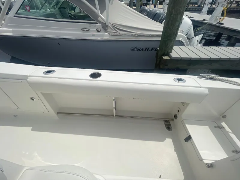 Slide: The Image of 2016 Sea Hunt Gamefish 27 boat interior, featuring seating and storage compartments at a marina. - 41