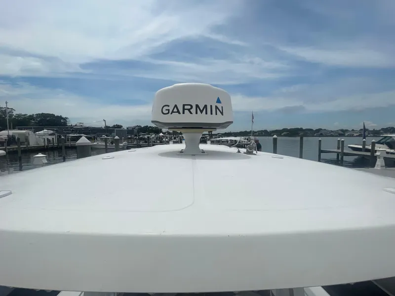 Slide: The Image of 2016 Sea Hunt Gamefish 27 boat with Garmin radar, docked at a marina under a cloudy sky. - 46