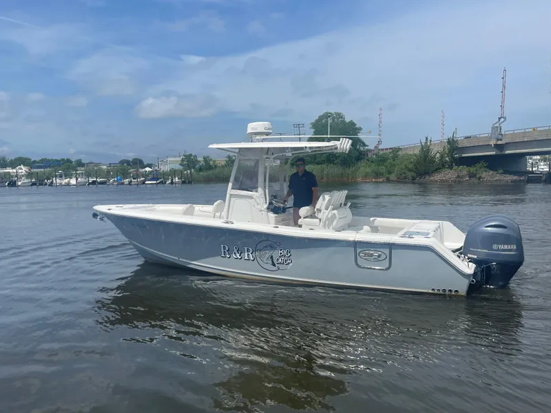 Slide: The Image of 2016 Sea Hunt Gamefish 27 boat on calm water near a bridge. - 6