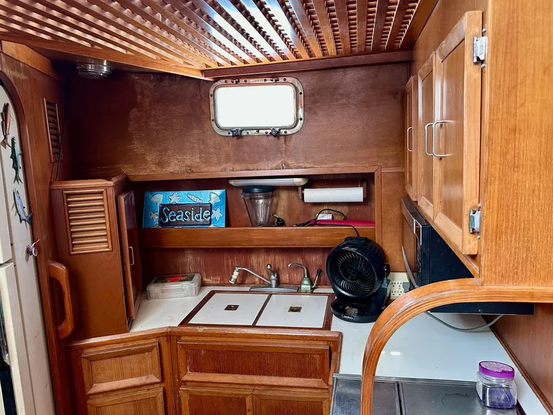 Slide: The Image of 1987 Jefferson Sundeck yacht kitchen with wooden cabinets, sink, and nautical decor. - 17