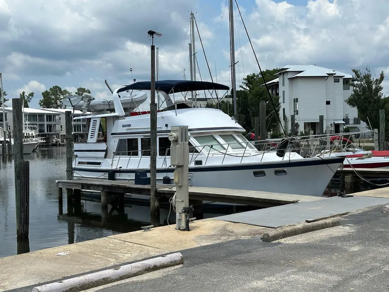 Slide: The Image of 1987 Jefferson Sundeck yacht docked at a marina under cloudy skies. - 2