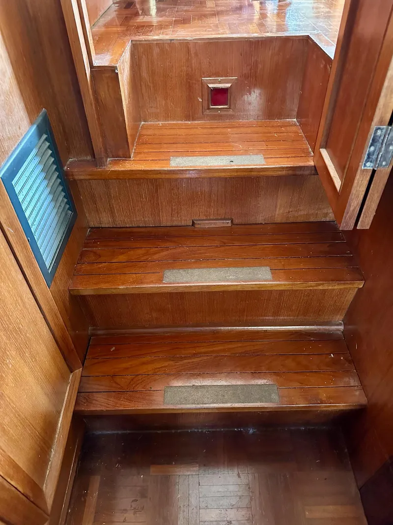 Slide: The Image of Wooden stairs inside a 1987 Jefferson Sundeck boat, featuring polished steps and a vent. - 33