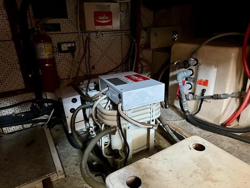 Slide: The Image of Engine room of a 1987 Jefferson Sundeck boat with machinery and wiring. - 39