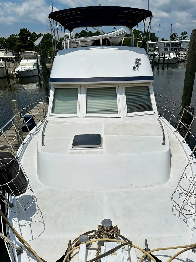 Slide: The Image of 1987 Jefferson Sundeck yacht docked at marina, featuring spacious deck and windows. - 5