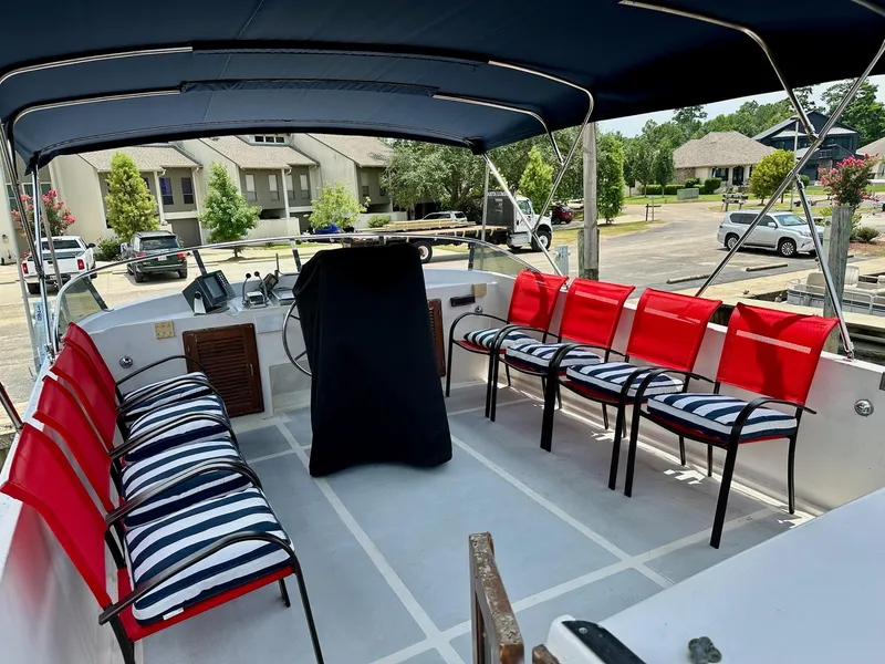 Slide: The Image of 1987 Jefferson Sundeck boat interior with striped cushions and red chairs under a canopy. - 9