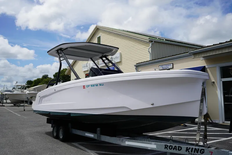 Slide: The Image of 2022 Axopar 22 T-Top boat on trailer, parked outside a dealership under a cloudy sky. - 2