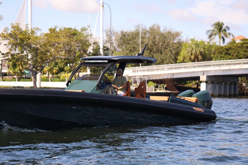 Slide: The Image of 2025 Skipper-BSK 38 boat cruising on a sunny day near a bridge and lush greenery. - 16