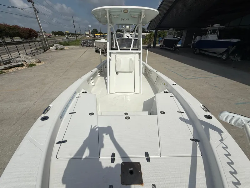 Slide: The Image of 2018 BlackJack 256 boat on display at a dealership, showcasing spacious deck and console. - 12