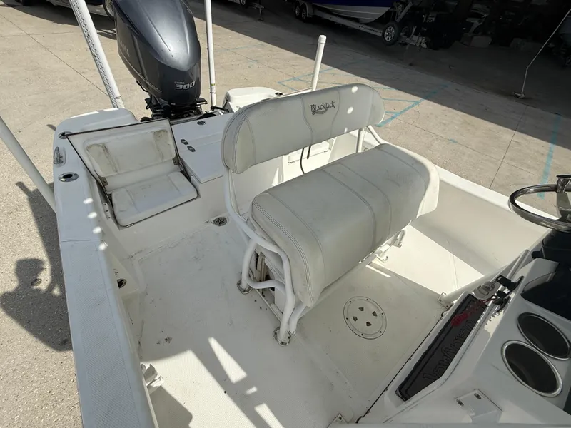 Slide: The Image of 2018 BlackJack 256 boat interior with seating and engine, parked on concrete. - 13