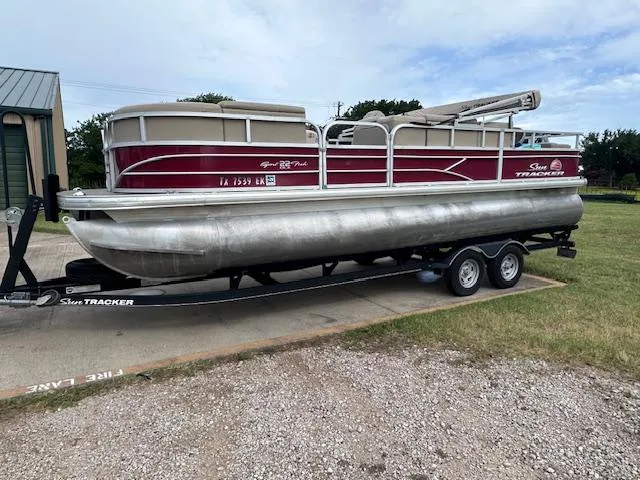 Slide: The Image of 2019 Sun Tracker SportFish 22 DLX pontoon boat on trailer, parked outdoors. - 2