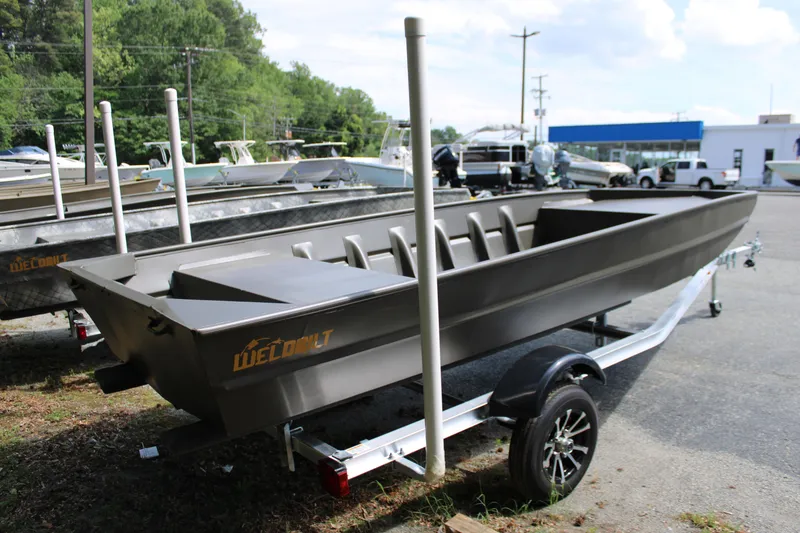 Slide: The Image of 2025 WeldBilt 1652V boat on trailer, parked outdoors, surrounded by trees and other boats. - 7