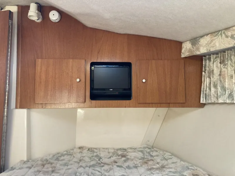 Slide: The Image of 1996 Carver 320 Voyager cabin interior with wood paneling, small TV, and patterned bedding. - 13