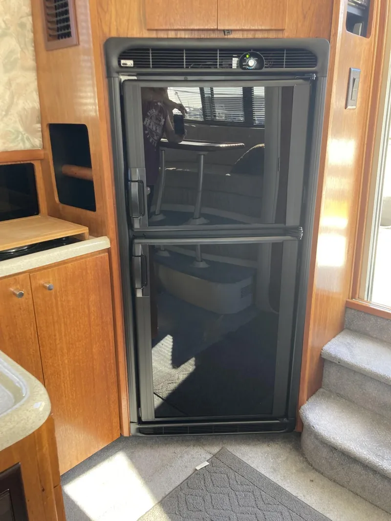 Slide: The Image of 1996 Carver 320 Voyager interior with a black refrigerator and wooden cabinetry. - 15