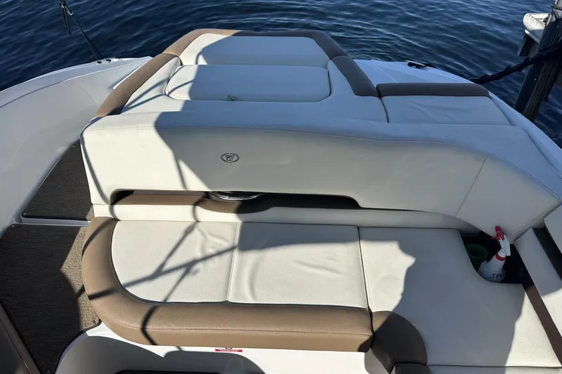 Slide: The Image of 2018 Cobalt CS23 boat interior with cushioned seating, docked on calm water. - 8