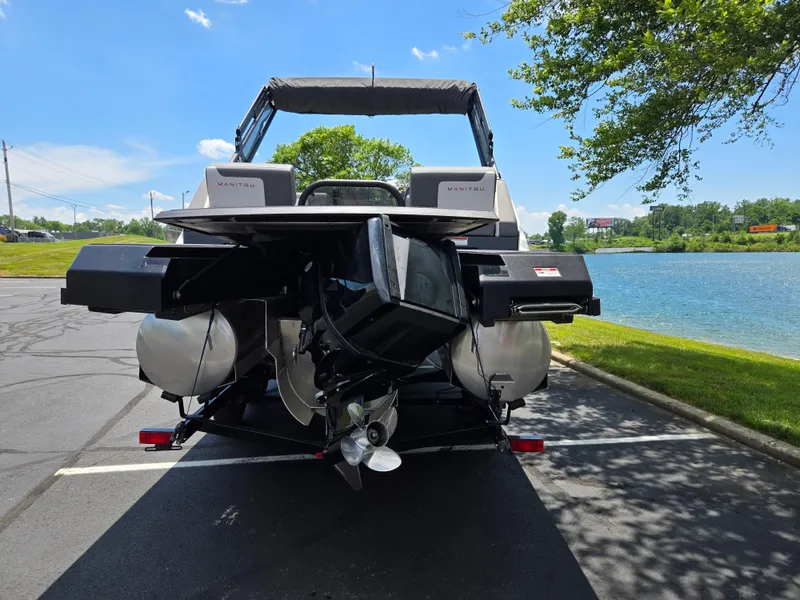 Slide: The Image of 2024 Manitou Cruise pontoon boat parked near a scenic lake. - 2