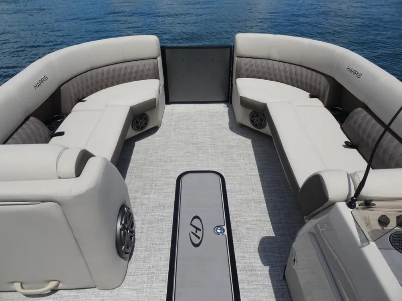 Slide: The Image of 2023 Harris Sunliner 250 boat interior with plush seating and speakers, on calm water. - 19